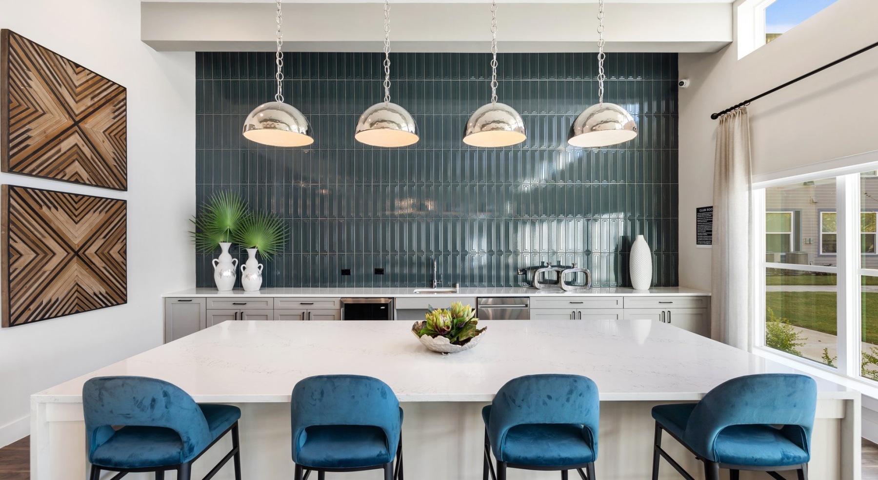 a spacious resident lounge with a large island, pendant lighting, and ample seating